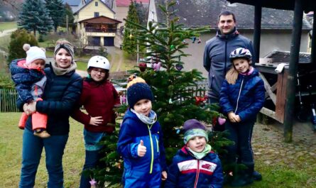 Kinder mit aufgestelltem und geschmückten Weihnachtsbaum